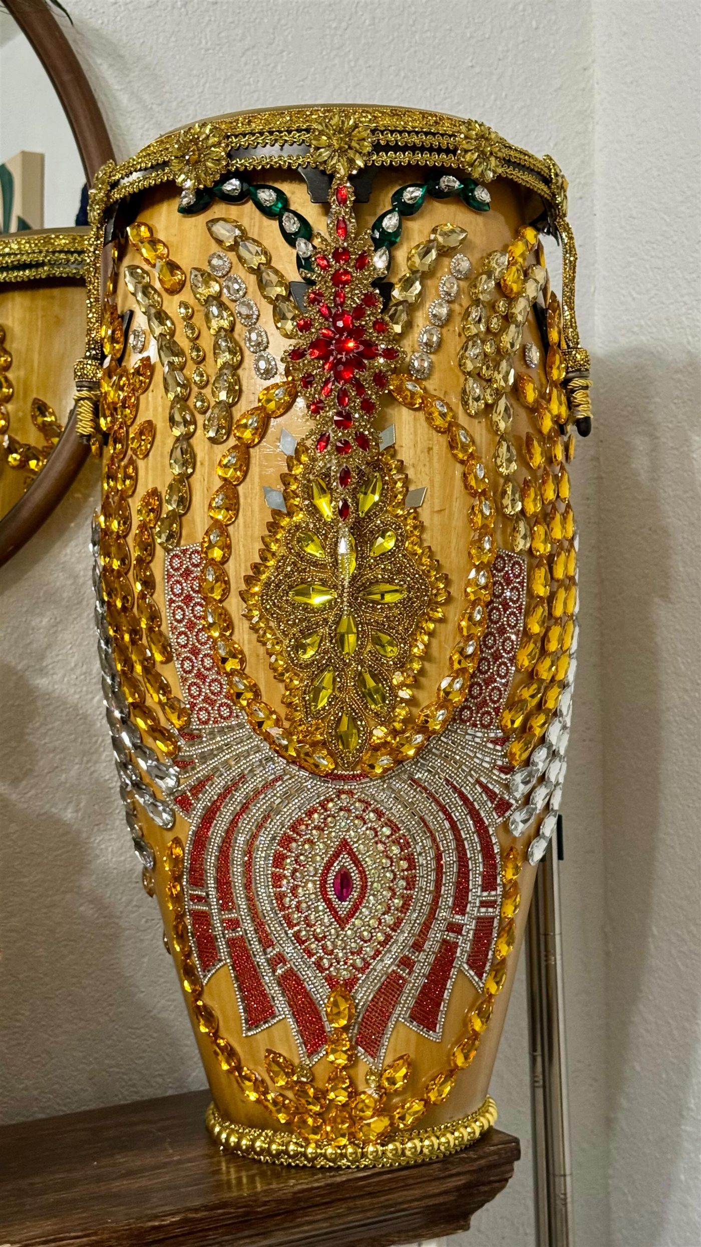 Tambor de Ochún sobre madera decorado con cristales amarillos, rojos y plateados